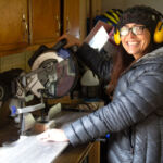 Steph smiling about to cut some flooring with the saw.