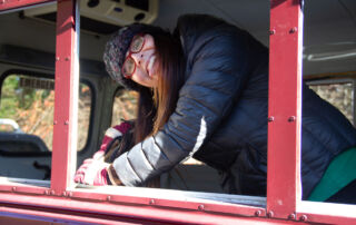Steph smiling in empty window hole.