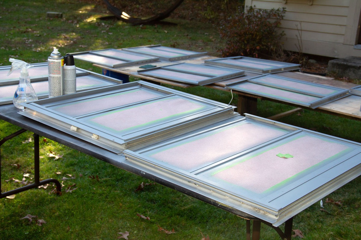 Several primed windows on two tables in the yard. 