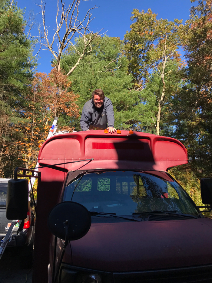 Kris on top of bus with a scraper.