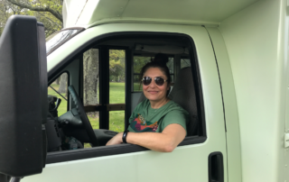 Steph in the driver's seat of the painted bus.